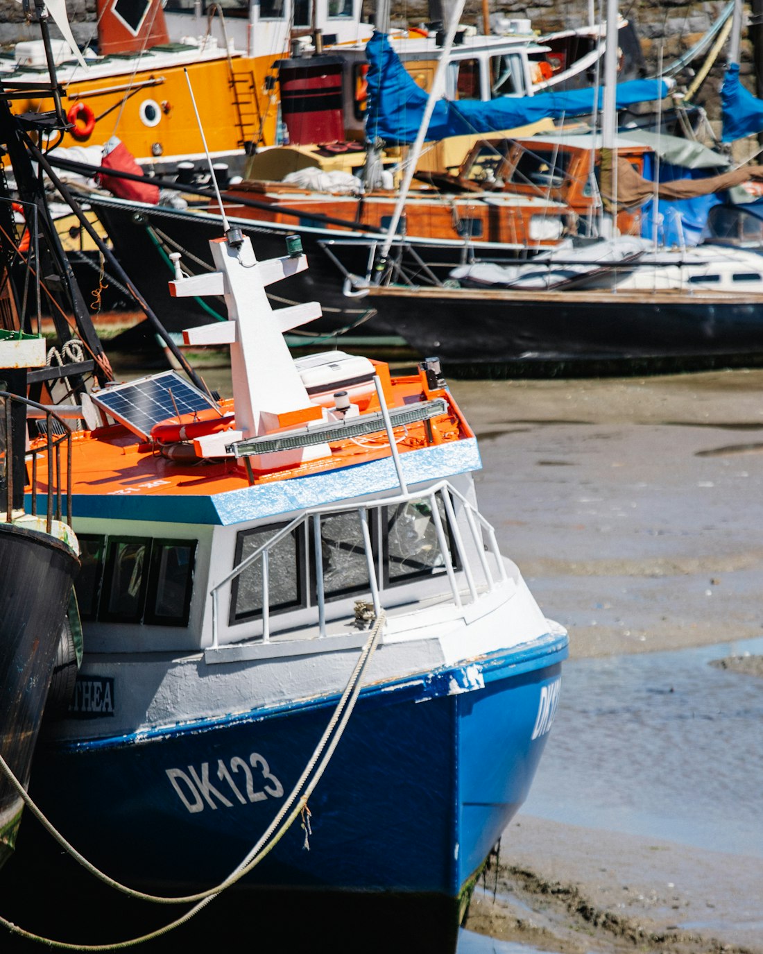 A blue and orange boat aground at low tide