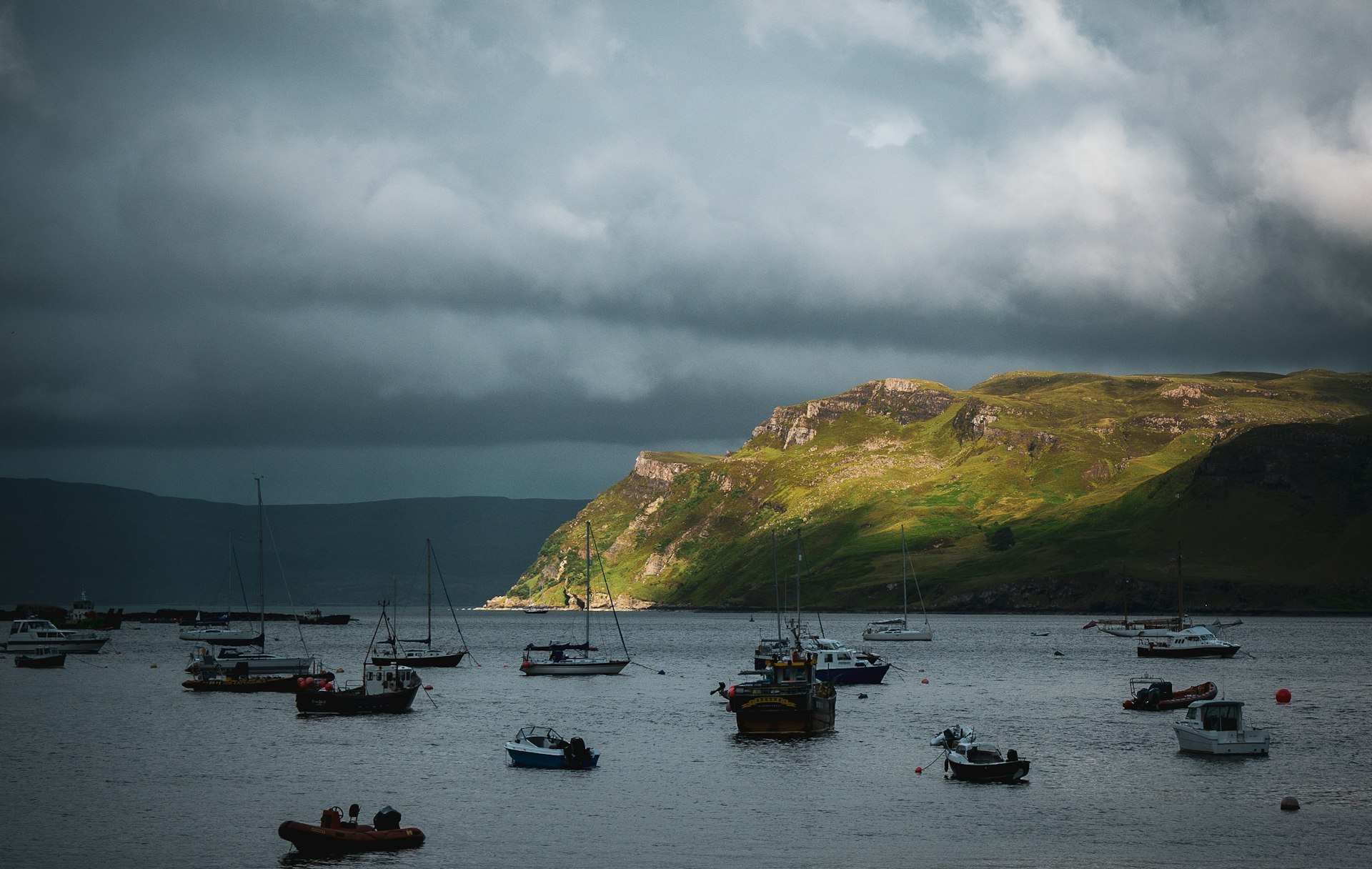 Boats at anchor under a break in storm light