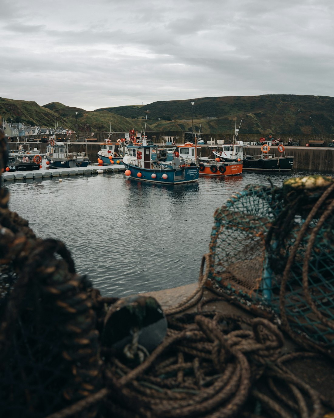 Creels and coiled rope on the quay, the fleet at its moorings behind