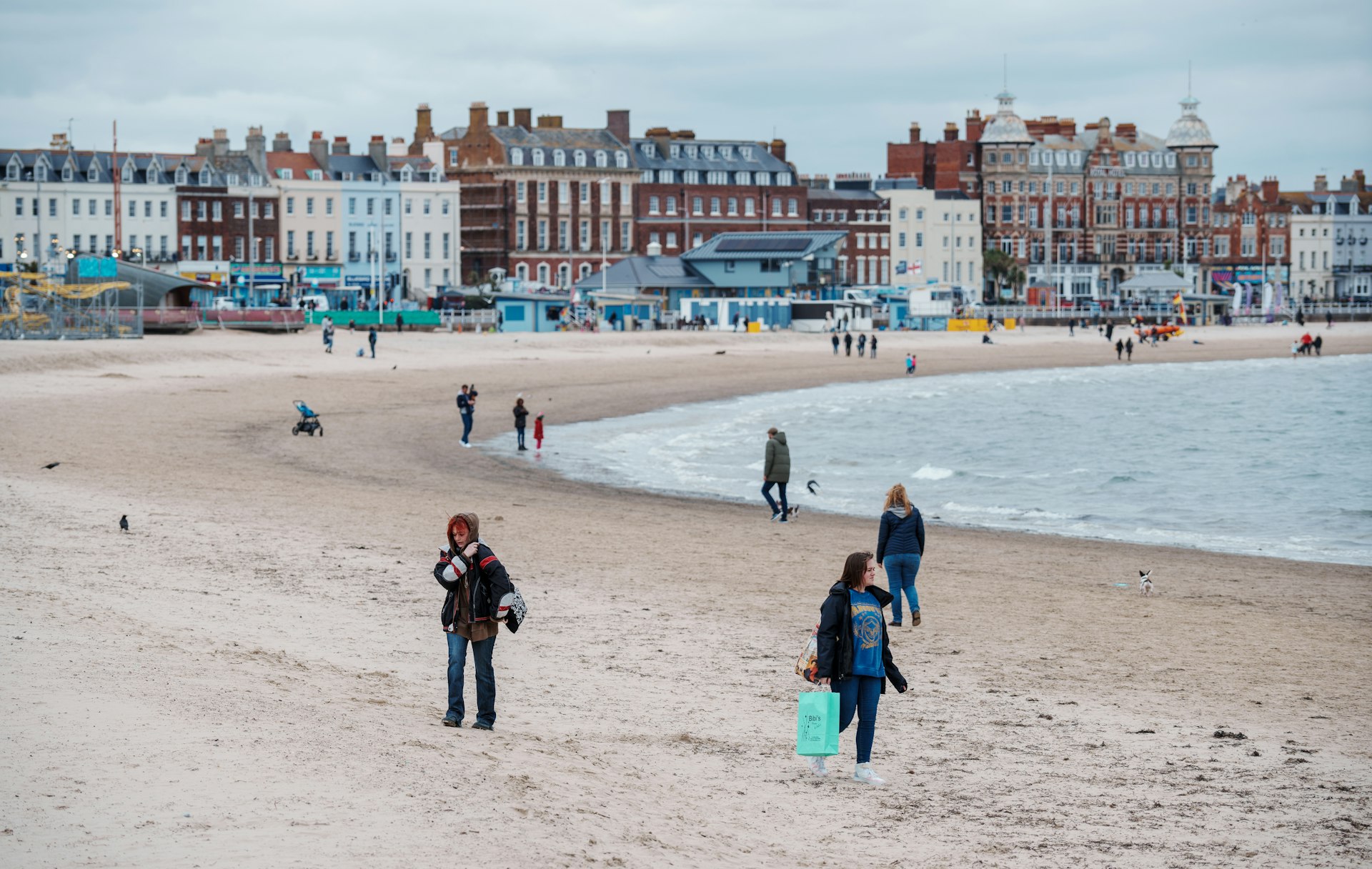 Walkers crossing the winter beach below the town