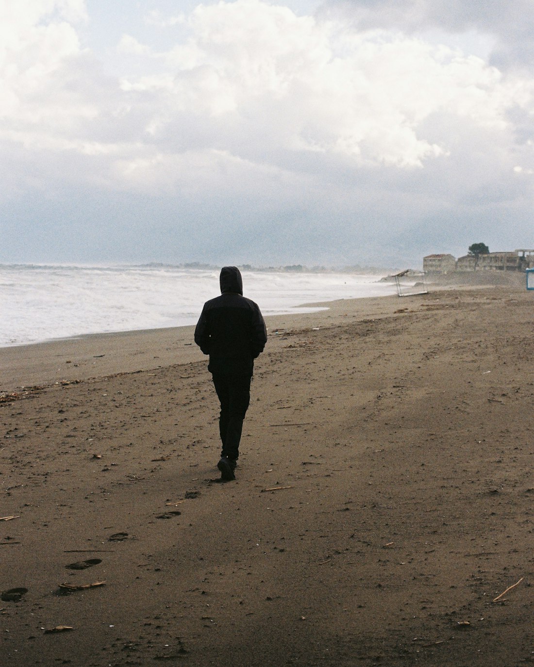 A walker in a dark coat on the winter beach
